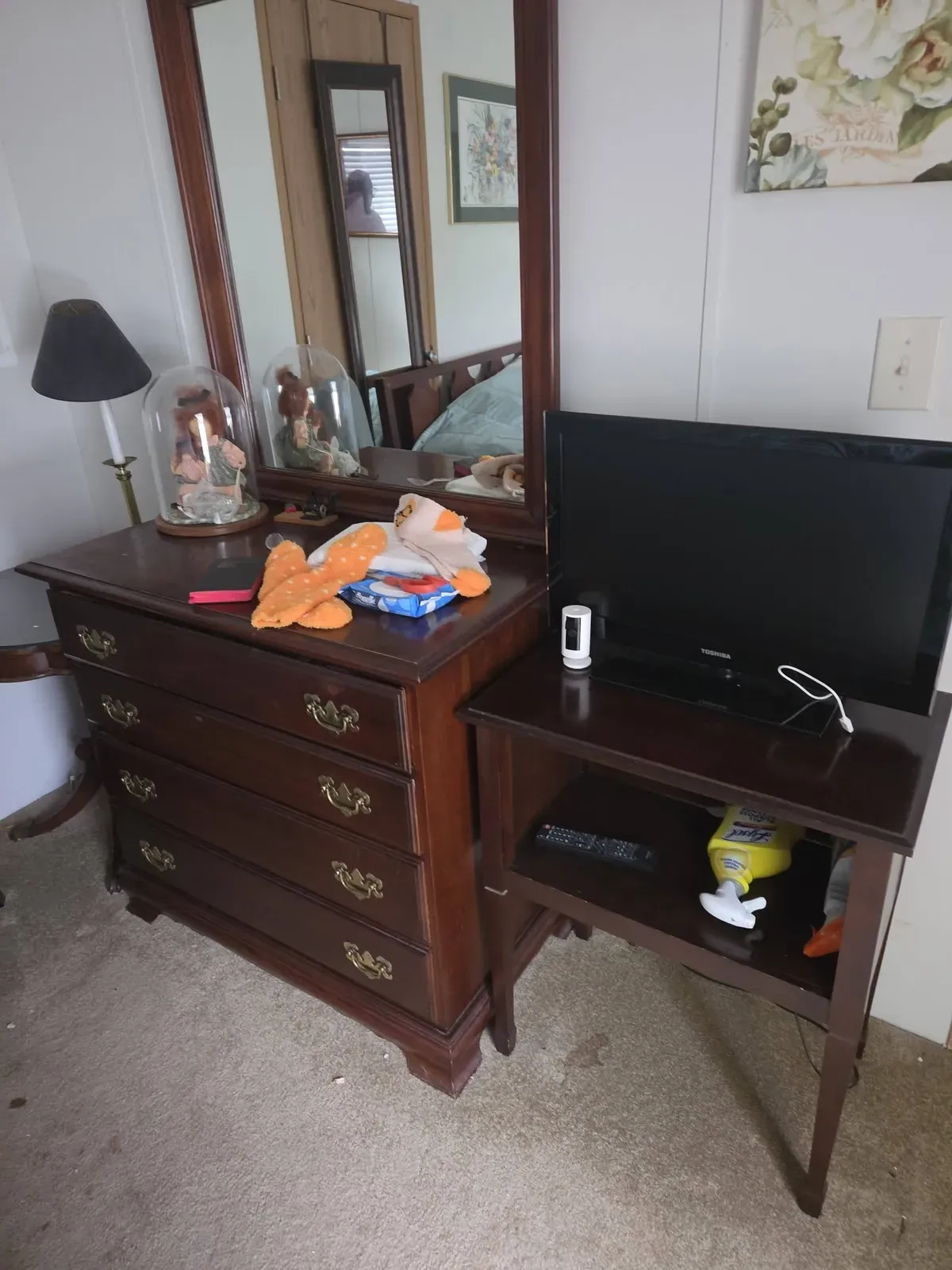 Wooden dresser with a mirror and a small TV stand in a bedroom