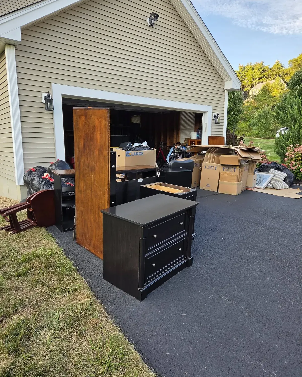 Dresser, nightstand, wardrobe door and boxes set out in a driveway