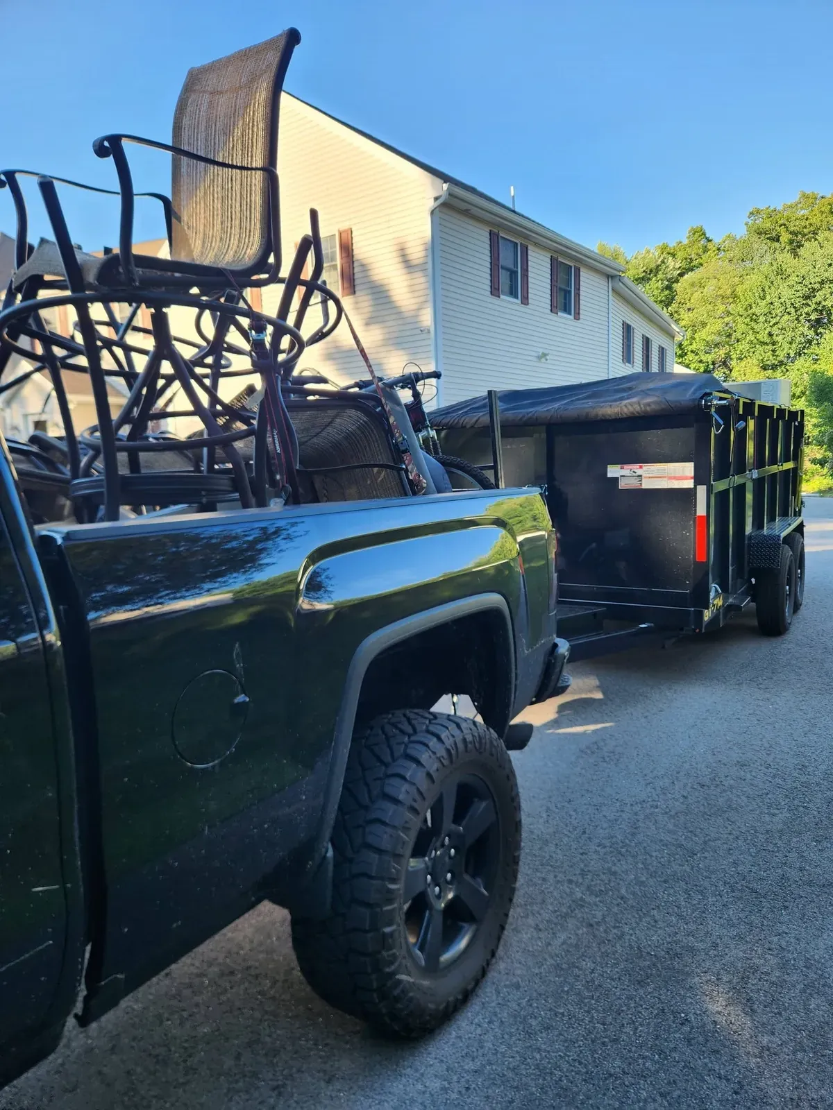 Patio chairs stacked in the truck bed with the dump trailer behind