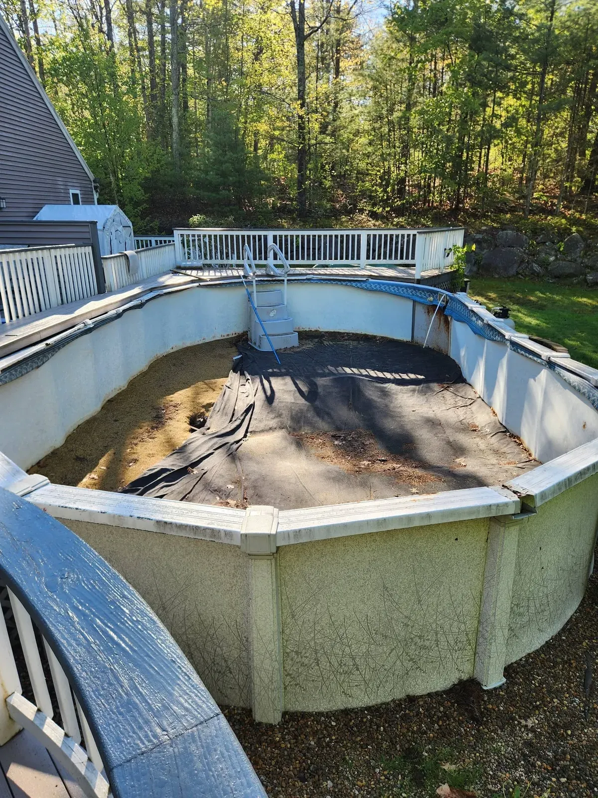 Drained above-ground pool beside a deck before demolition
