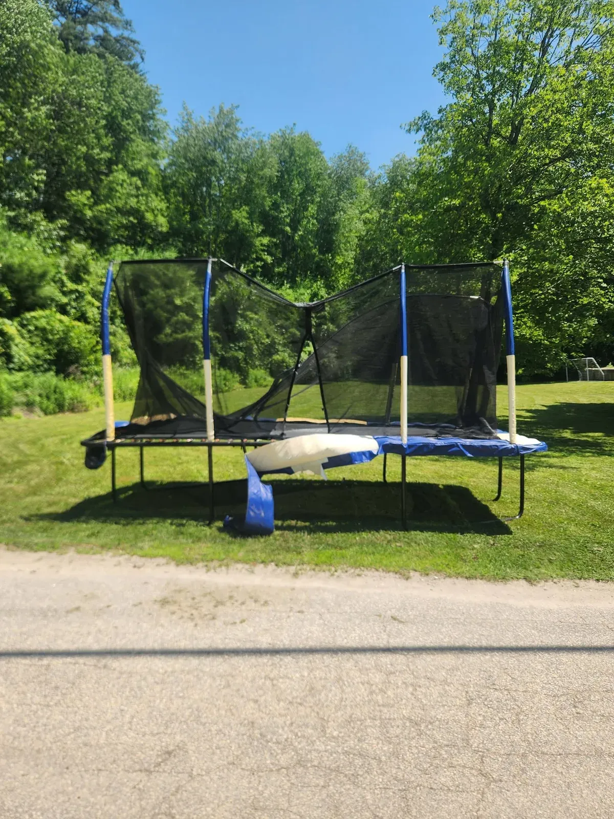 Old trampoline with a torn safety net in a backyard