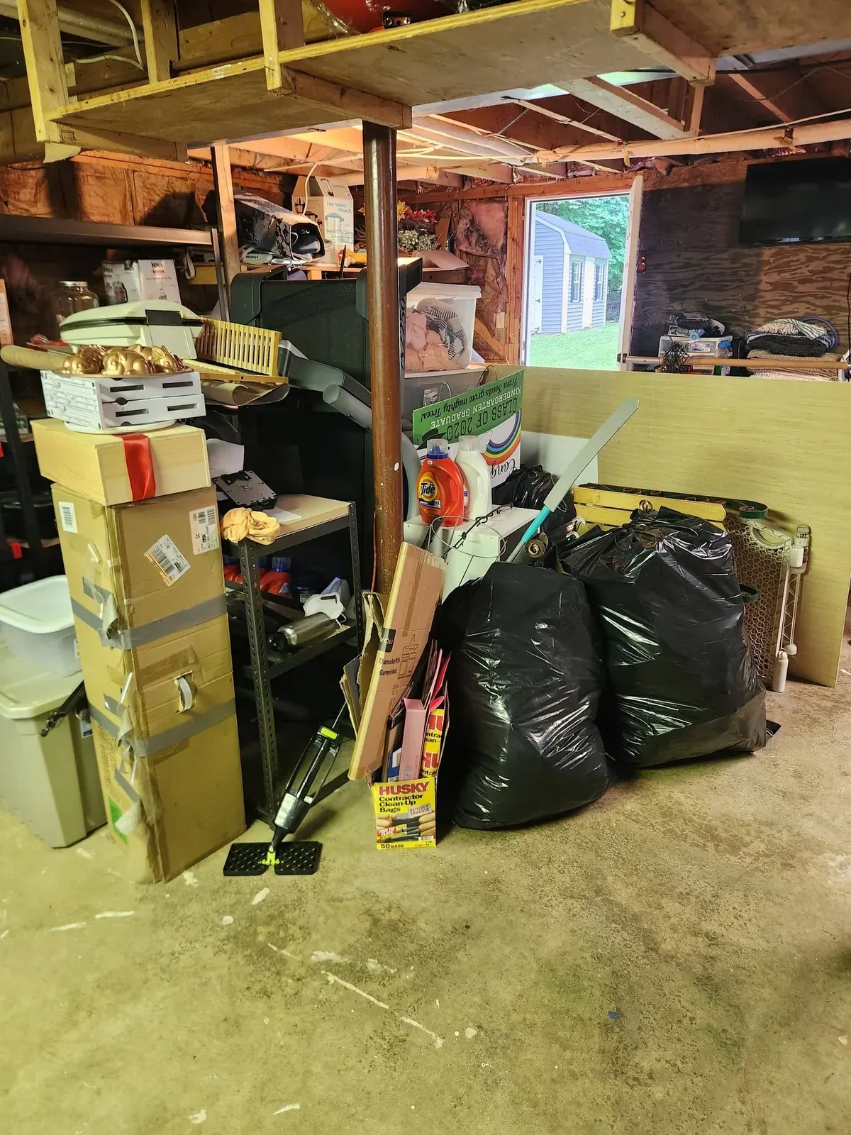 Basement crowded with boxes, trash bags and shelving before a cleanout