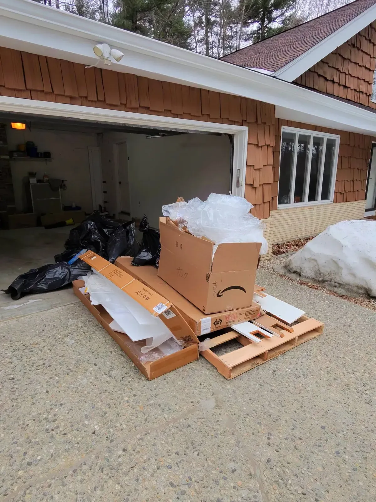 Cardboard boxes, packing foam and wooden pallets piled in front of an open garage