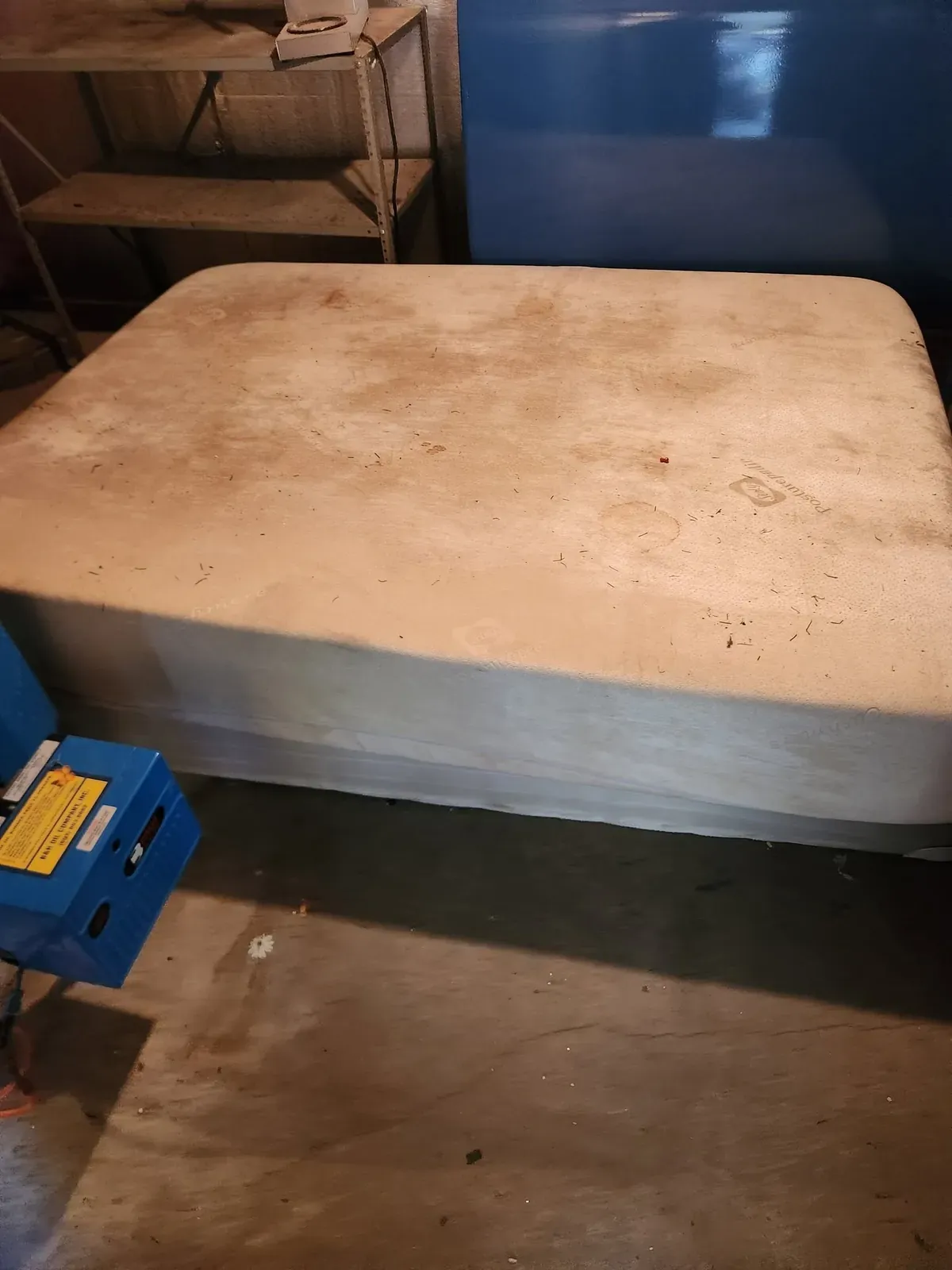 Worn mattress and box spring in a basement